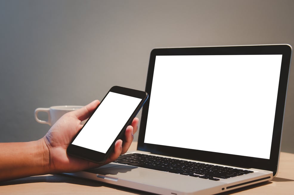 man hand holding mobile smartphone and computer laptop mock